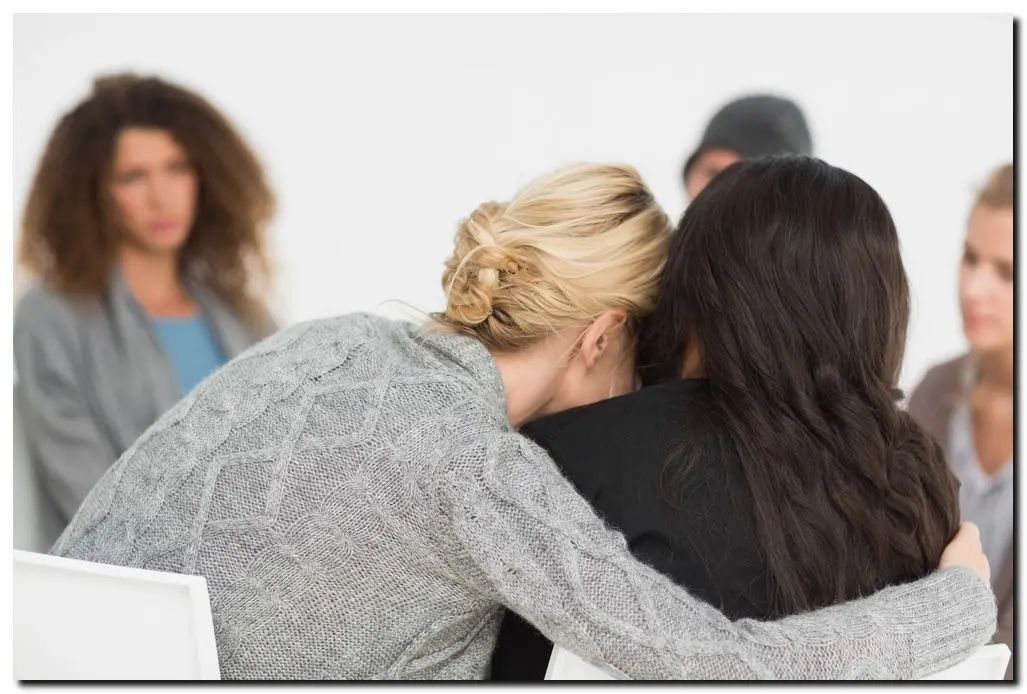 group members in a circle, one female hugging another at Drug Rehabilitation Centers in Nebraska